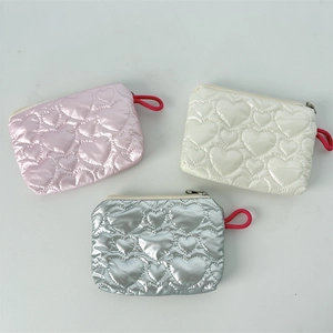 Detailed view of heart-quilted PU leather makeup pouches in pink, white, and silver colors