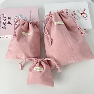 Close-up of pink crinkle fabric drawstring bags in various sizes with woven labels