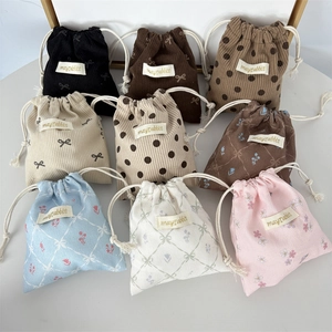 Macro shot of assorted corduroy drawstring bags with floral prints and woven labels