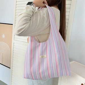 Detailed close-up of rainbow striped seersucker tote bag with brand label and soft texture