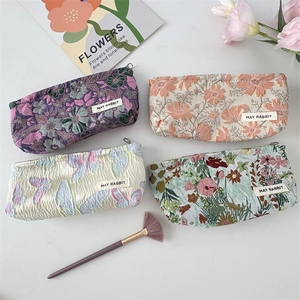 Detail of four jacquard floral makeup bags with intricate embossed butterfly patterns