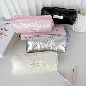 Quilted ribbon bow stationery pouches in four colors on a desk with books