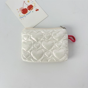 Top view of white heart-quilted PU pouch with zipper closure and red lanyard on white background