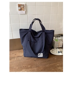 Detail of navy blue nylon tote bag showing white woven label and waterproof texture
