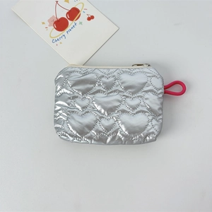 Macro view of silver heart-quilted PU leather pouch with metallic finish and red strap