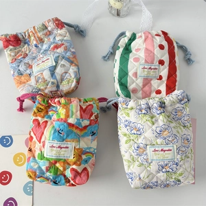 Detailed view of four quilted cotton drawstring bags with various colorful printed patterns