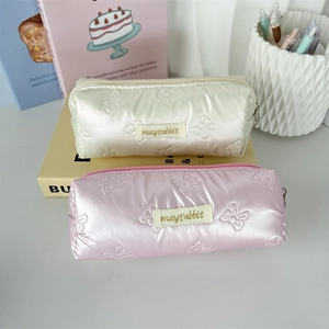 Detailed view of quilted PU pencil cases with bow patterns and woven brand label