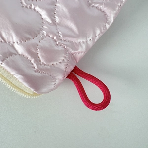 Detail of pink satin heart quilted makeup bag with red lanyard and cream zipper