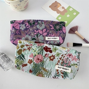 Detailed view of French jacquard floral makeup bags with intricate embossed fabric texture