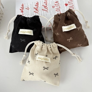Corduroy drawstring storage bags with cute bow prints in black, brown, and cream white
