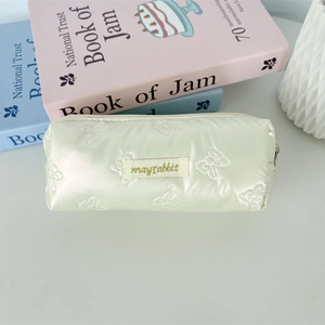 Detailed view of cream quilted bow embroidery pencil case with mayrabbit label tag