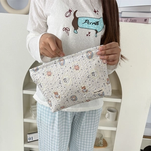 Détail d'une trousse de maquillage matelassée avec rayures bleues et motif ours mignon