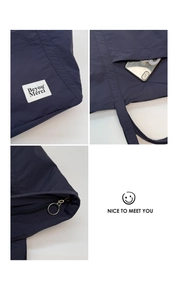 Detail of navy nylon tote bag showing white embroidered label and front phone pocket