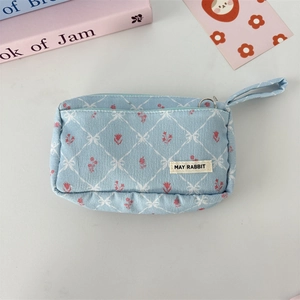 Detail of light blue corduroy pouch with floral embroidery and diamond quilt pattern