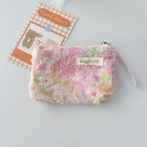 Close-up of floral lace makeup bag with pink ribbon zipper and brand fabric label