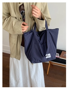 Navy nylon tote bag styled with a trench coat for a minimalist commuting look