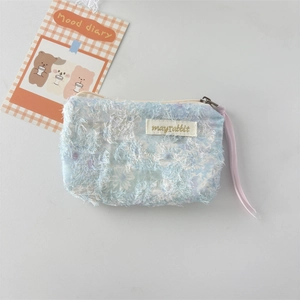 Detail of light blue fuzzy makeup pouch with gold embroidery and purple ribbon pull