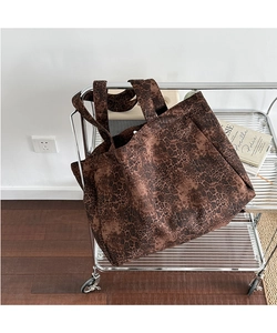 Detail of a large leopard print canvas tote bag resting on a silver cart in a studio