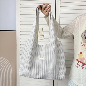 Detail of grey striped tote bag in seersucker fabric with rectangular woven label