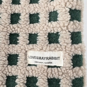 Gros plan d'un sac cabas en peluche à damier avec texture laineuse et étiquette