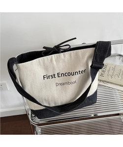 Detail of herringbone canvas tote bag with First Encounter embroidery and denim base