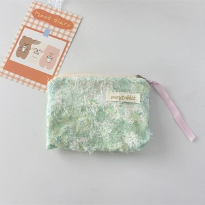 Close-up of green floral lace cosmetic pouch with fuzzy fabric texture and zipper detail