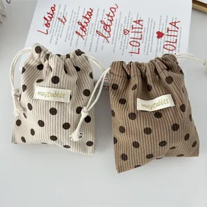 Close-up of corduroy drawstring pouches in beige and brown with polka dot patterns