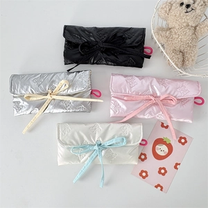 Quilted bow-patterned pouches in black, silver, pink, and white with ribbon tie closure