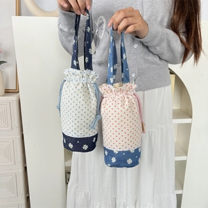 Dettaglio della borsa porta borraccia con coulisse, pois e motivi floreali patchwork