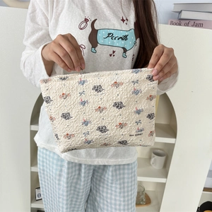 Détail d'une trousse de maquillage beige avec motifs d'éléphants en relief