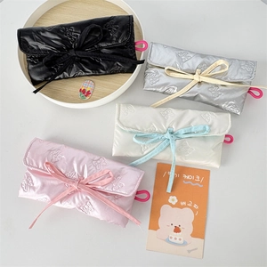 Detailed close-up of quilted bow-knot storage pouches in black, silver, beige and pink colors