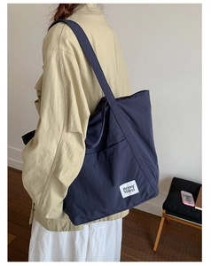 Detail view of the large capacity navy nylon tote bag showing its practical side pocket
