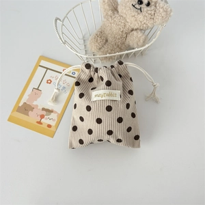Detail view of corduroy drawstring bag with polka dots and woven brand label