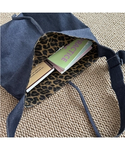 Detail of blue denim tote bag with leopard print lining and contrast stitching