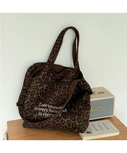 Detalle de bolso tote con estampado de leopardo y texto inspirador sobre madera