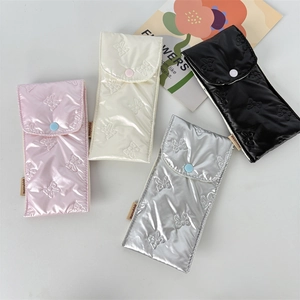 Detailed overhead shot of four quilted bow eyeglass pouches in pink, white, silver, and black