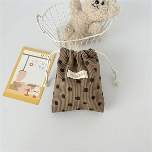 Detailed view of brown polka dot corduroy drawstring bag with a woven brand label