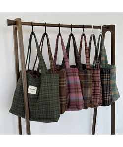 Hanging display of vintage plaid tote bags in various colors on a wooden rack