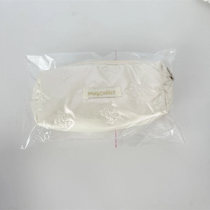 Detail of cream pencil case with butterfly quilted pattern and mayrabbit label in packaging
