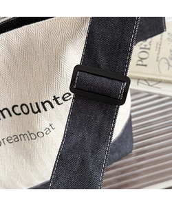 Detail of adjustable black strap and printed herringbone canvas tote bag