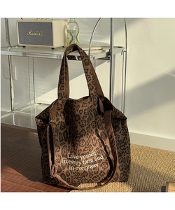 Detalle del bolso tote de leopardo con texto blanco en una escena con luz solar