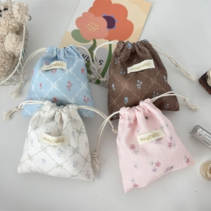 Detailed close-up of four floral corduroy drawstring bags in blue, pink, white and brown