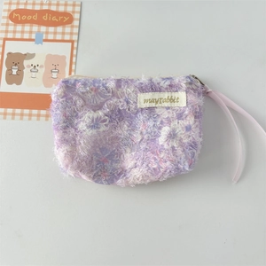 Detailed macro view of purple floral plush pouch with lace zipper and ribbon puller