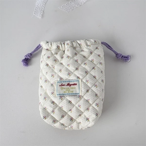 Close-up of quilted floral camera bag with purple drawstring and soft cotton texture