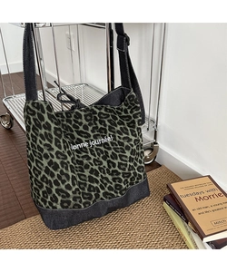 Detail of leopard print canvas tote bag featuring white French text and reinforced base