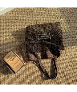 Detalle de la bolsa tote de lona con estampado de leopardo y letras blancas inspiradoras