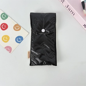 Detailed view of black quilted pencil case with bow texture and button closure
