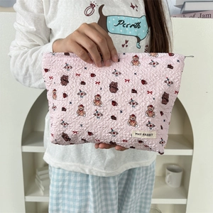 Détail de la trousse à maquillage rose matelassée avec motifs d'ours et gâteaux