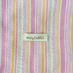Detail of multi-colored seersucker fabric texture with a mayrabbit woven brand label
