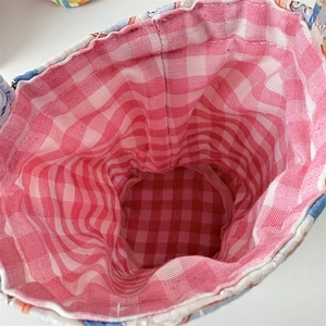 Detailed close-up of a quilted fabric bag featuring a red and white gingham inner lining